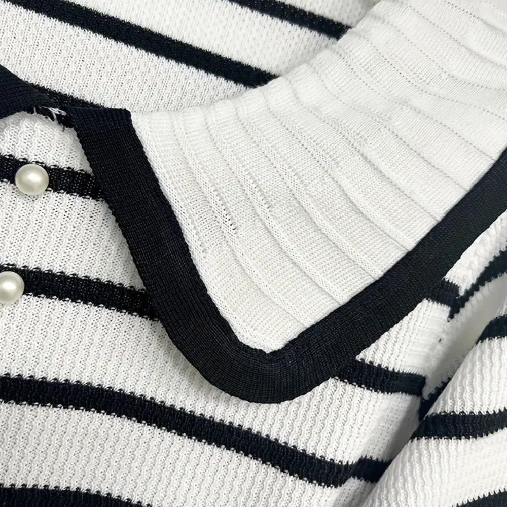 Gestreepte trui met zwart-witte strepen, grote kraag en parelknopen. Modieuze dameskleding, trendy design, comfortabele stof.