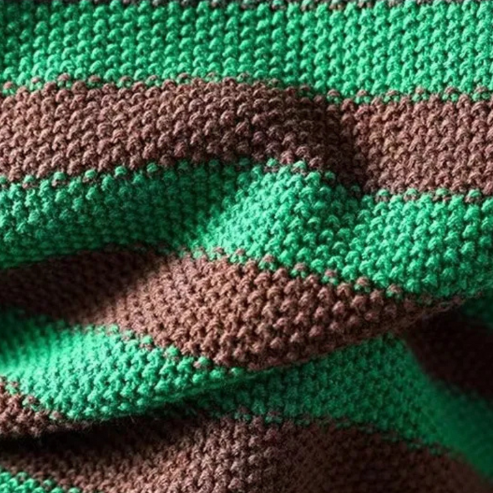 Gestreepte gebreide deken in groen en bruin, close-up textuur. Perfect voor interieurdecoratie, warme en gezellige uitstraling, handgemaakt breiwerk.