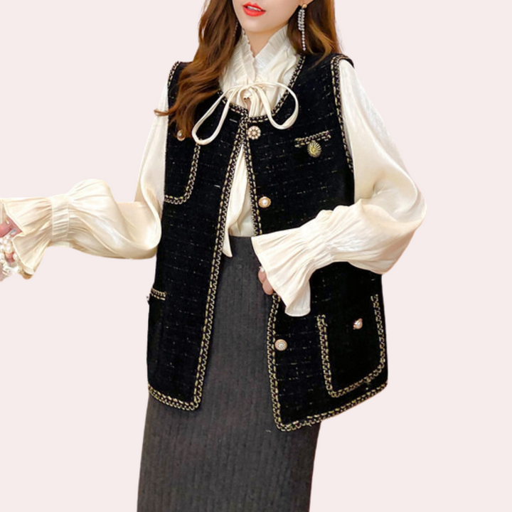 Vrouw in elegante outfit met zwarte, geborduurde gilet, witte blouse met ruches en grijze rok. Modieuze dameskleding, herfststijl.