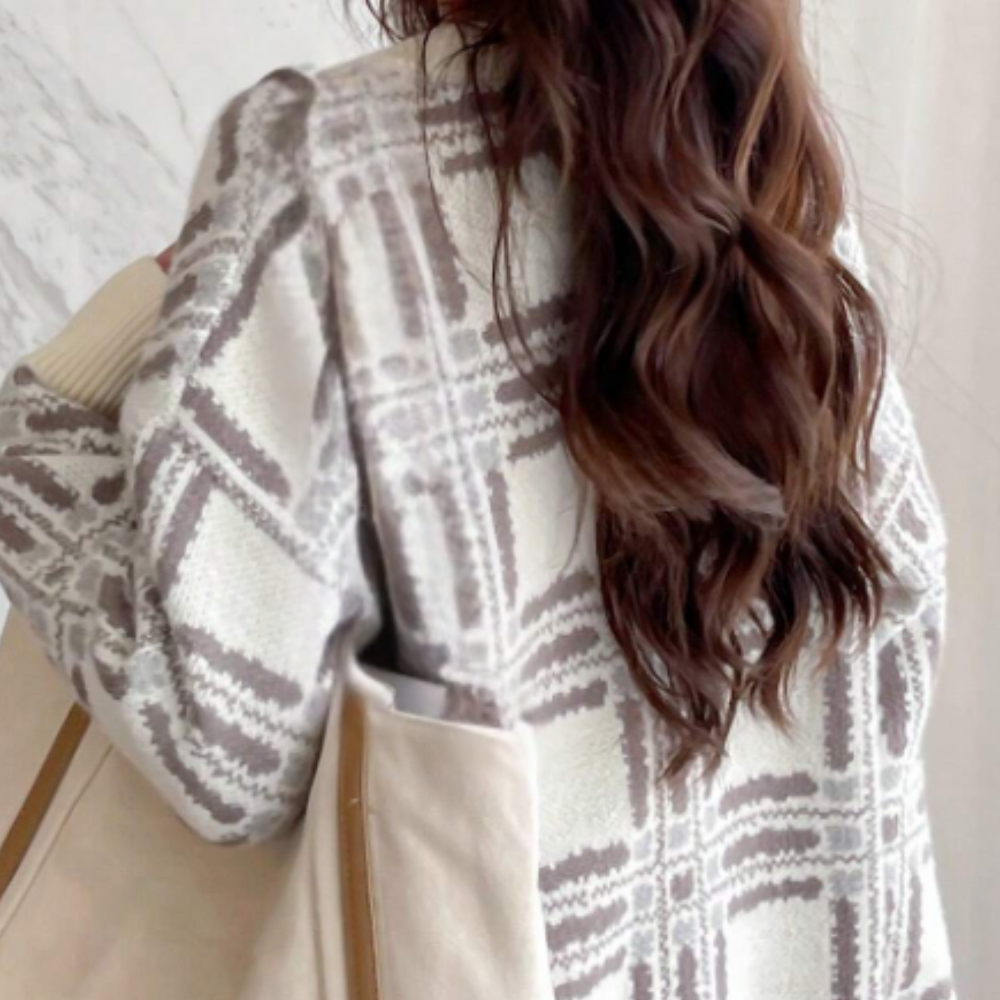Dame met lang bruin haar draagt een beige geruite jas en canvas tas. Modieuze herfstkleding, trendy damesmode, casual stijl.