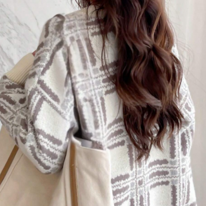 Dame met lang bruin haar draagt een beige geruite jas en canvas tas. Modieuze herfstkleding, trendy damesmode, casual stijl.