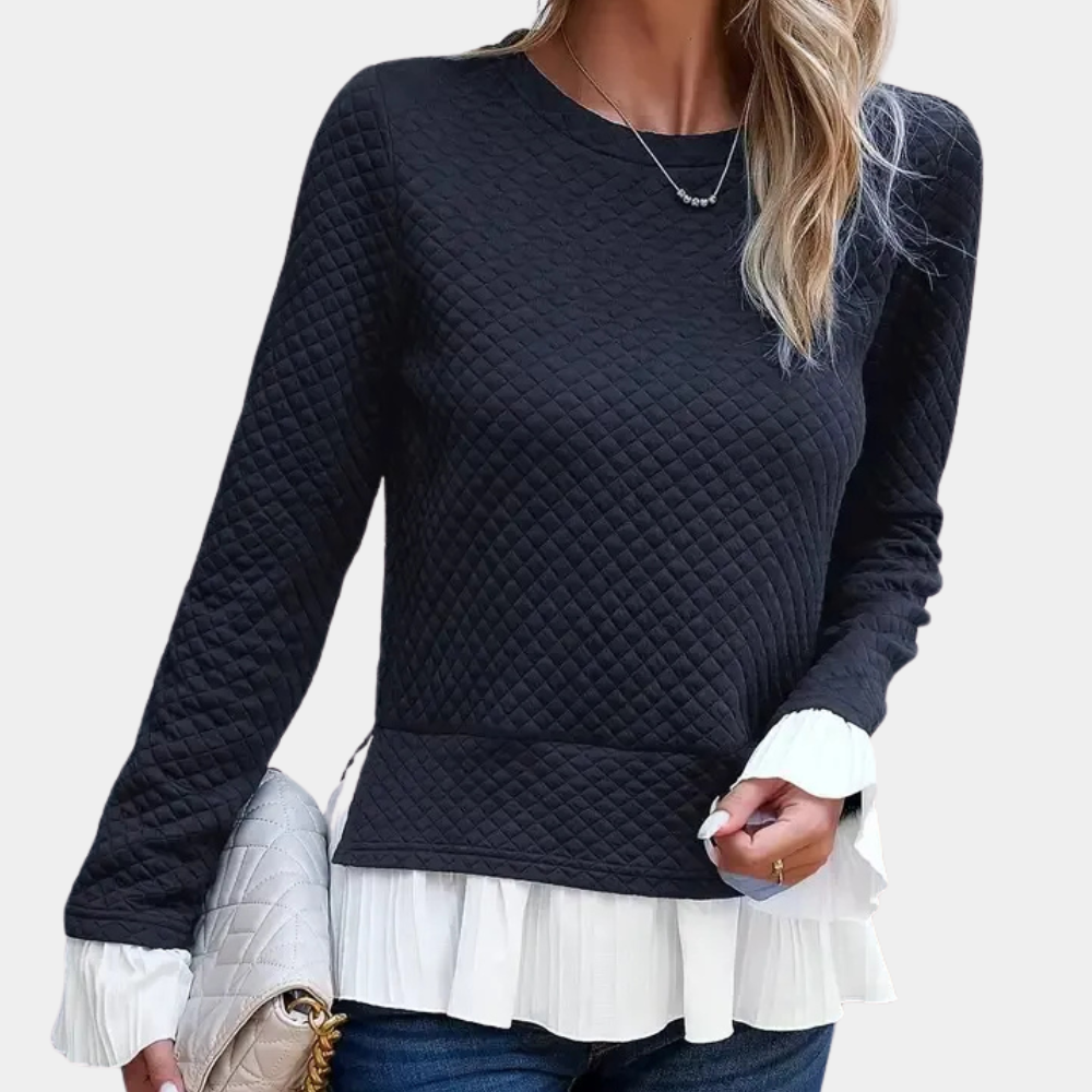 Vrouw in zwarte gewatteerde trui met witte ruches, draagt een beige gewatteerde tas. Modieuze dameskleding, herfstoutfit, casual stijl.