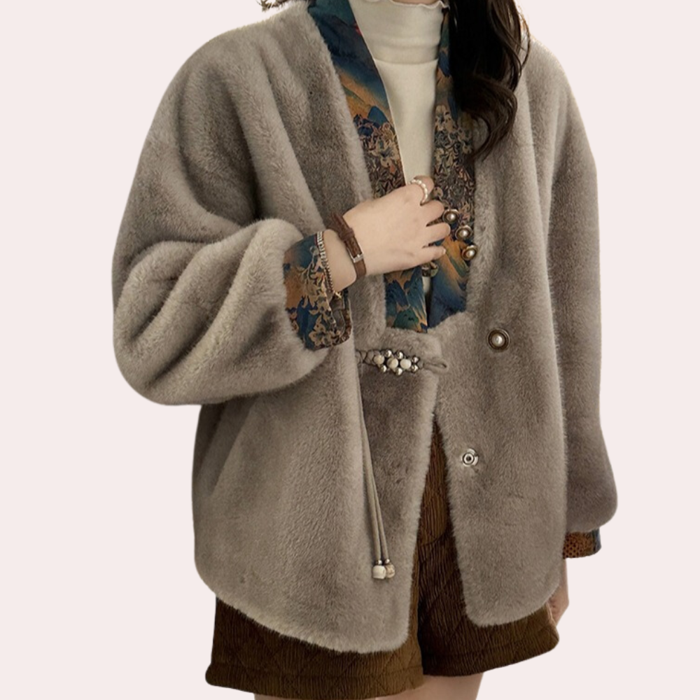 Grijze faux fur jas met kleurrijke sjaalkraag, gedragen door een vrouw. Modieuze winterjas, elegant design, warme dameskleding.