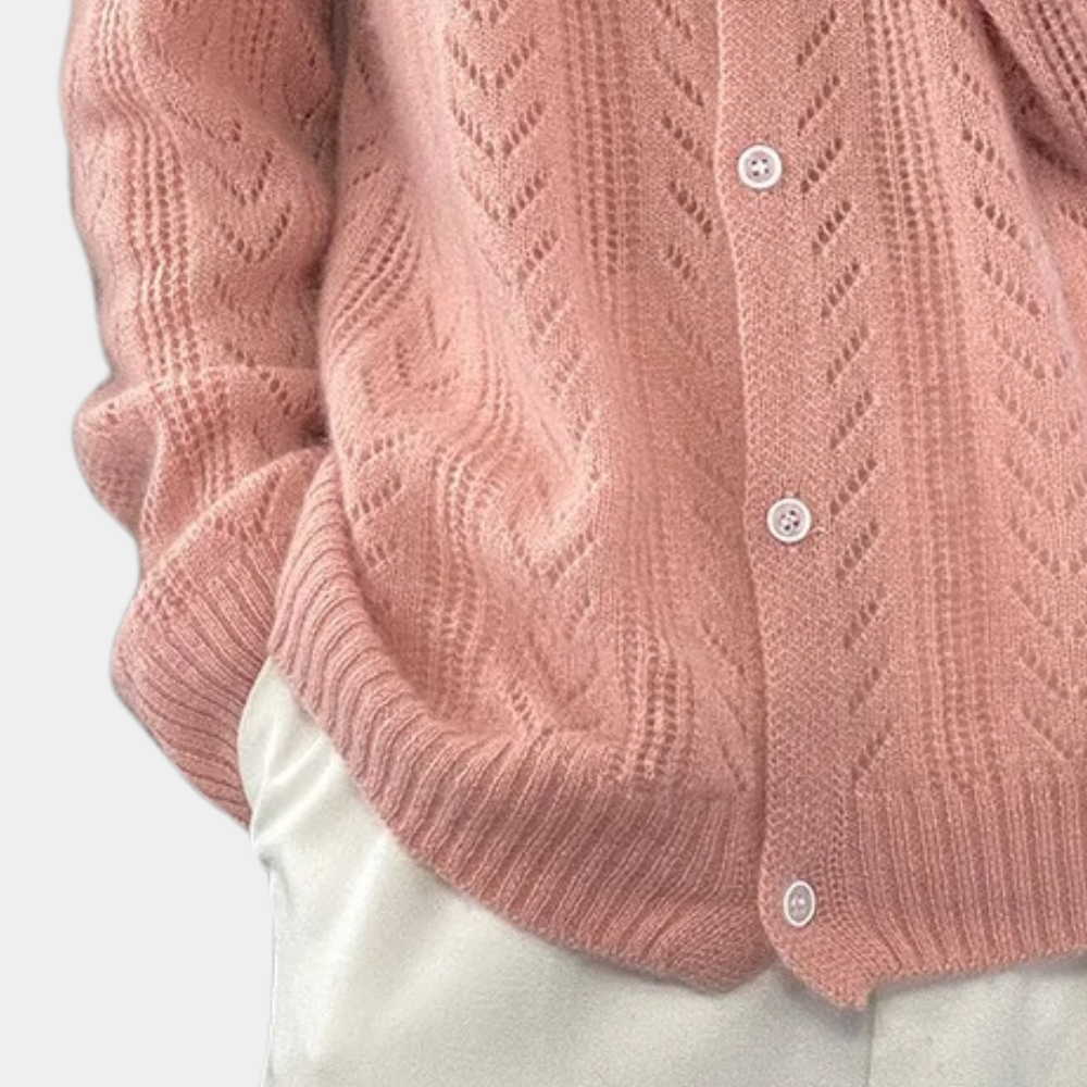 Roze gebreid vest met kabelpatroon en witte knopen, gedragen over een witte broek. Stijlvolle damesmode, herfstkleding, comfortabele outfit.