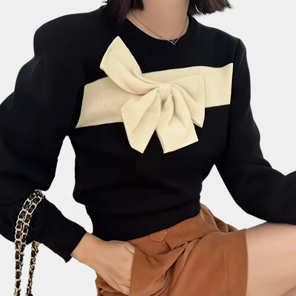 Vrouw draagt zwarte trui met grote crèmekleurige strik, gecombineerd met bruine rok. Modieuze dameskleding, herfstoutfit, stijlvolle trui.