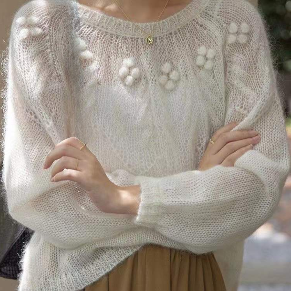 Vrouw in gebreide witte trui met bloemenpatroon, lange mouwen en ronde hals. Modieuze herfstkleding, casual stijl, zachte textuur.