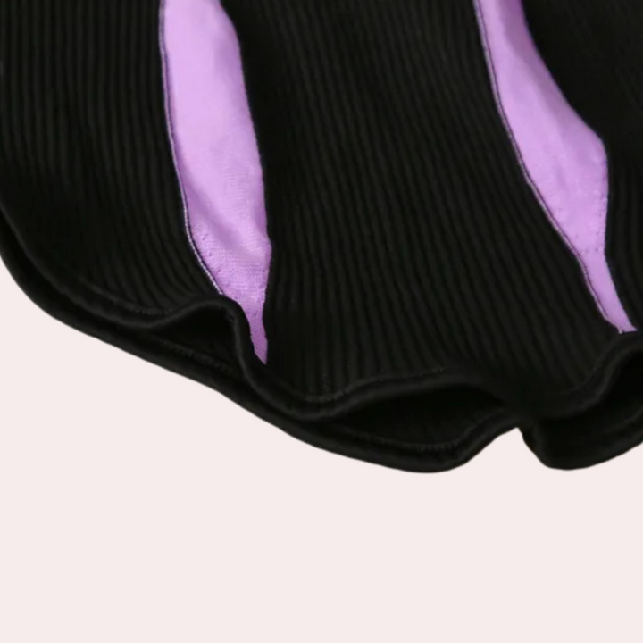 Zwarte geribbelde stof met paarse strepen, close-up textuur. Modetrend, textielontwerp, moderne kledingstof, detailopname.