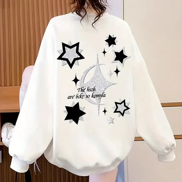 Witte oversized trui met zwarte en zilveren sterontwerpen, tekst "The fish are bkt so komyla", trendy mode, casual streetwear, dameskleding.