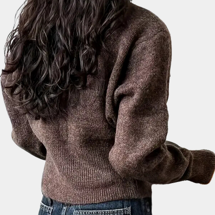 Bruine wollen trui dames, rugaanzicht, met lange mouwen en geribde taille, gecombineerd met blauwe jeans. Perfect voor herfstmode en casual outfits.
