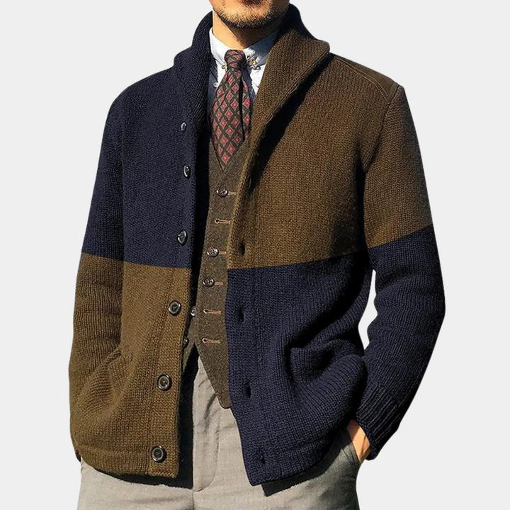 Man in stijlvolle, tweekleurige gebreide cardigan met bruine en marineblauwe strepen, gecombineerd met een geruite stropdas en grijze broek.