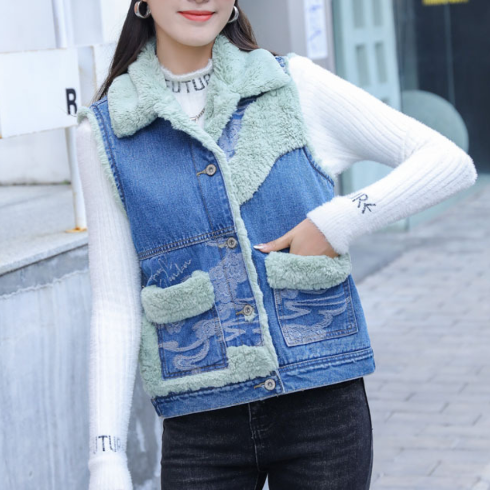 Vrouw draagt blauwe spijkerjas met groene fleece voering en zakken, witte trui eronder. Modieuze winterkleding, casual straatstijl.