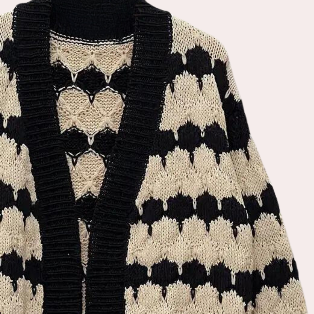 Zwart-beige gebreid vest met zigzagpatroon, open voorkant en grove textuur. Perfect voor herfstmode en casual outfits.