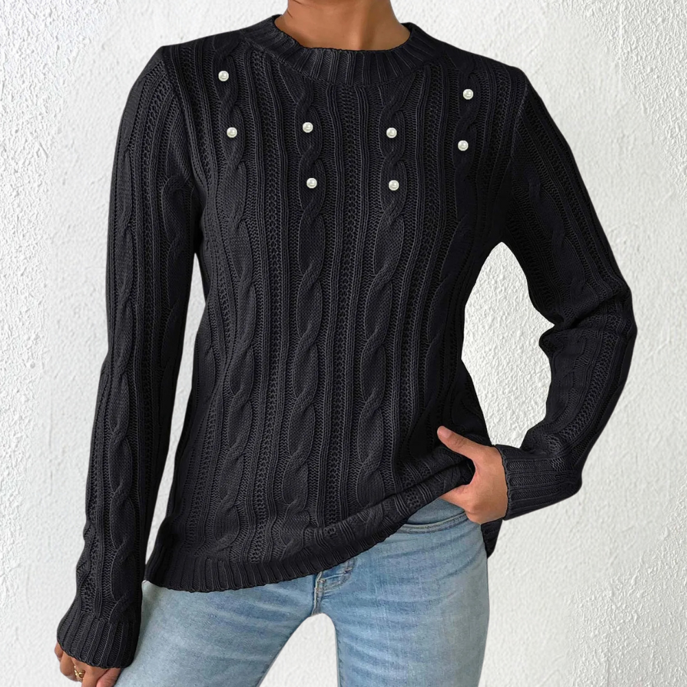 Zwarte kabeltrui met ronde hals en parelknopen, gedragen door model in blauwe jeans. Stijlvolle damesmode, herfstkleding, casual chic look.
