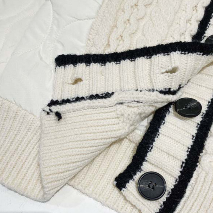 Witte gebreide trui met zwarte knopen en strepen, close-up. Modieuze dameskleding, wintermode, warme truien, stijlvolle gebreide kleding.