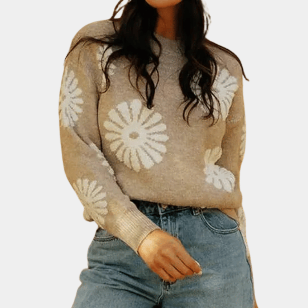 Vrouw draagt beige trui met witte bloemenprint en blauwe jeans. Modieuze dameskleding, casual outfit, herfstmode, trendy sweater.