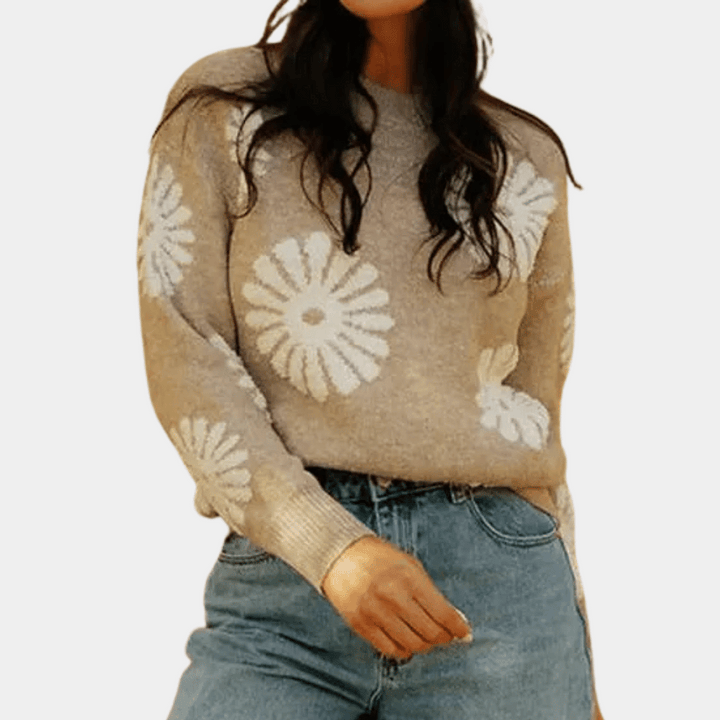 Vrouw draagt beige trui met witte bloemenprint en blauwe jeans. Modieuze dameskleding, casual outfit, herfstmode, trendy sweater.