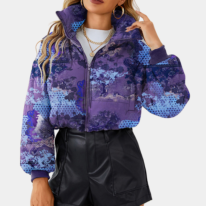 Vrouw draagt een paarse, grafische print jas met rits en hoge kraag, gecombineerd met zwarte leren shorts. Trendy damesmode, herfstkleding.