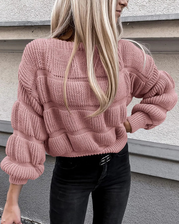 Vrouw in roze gebreide trui met ballonmouwen, casual outfit, modetrend herfst, straatstijl, lange blonde haren, zwarte jeans.