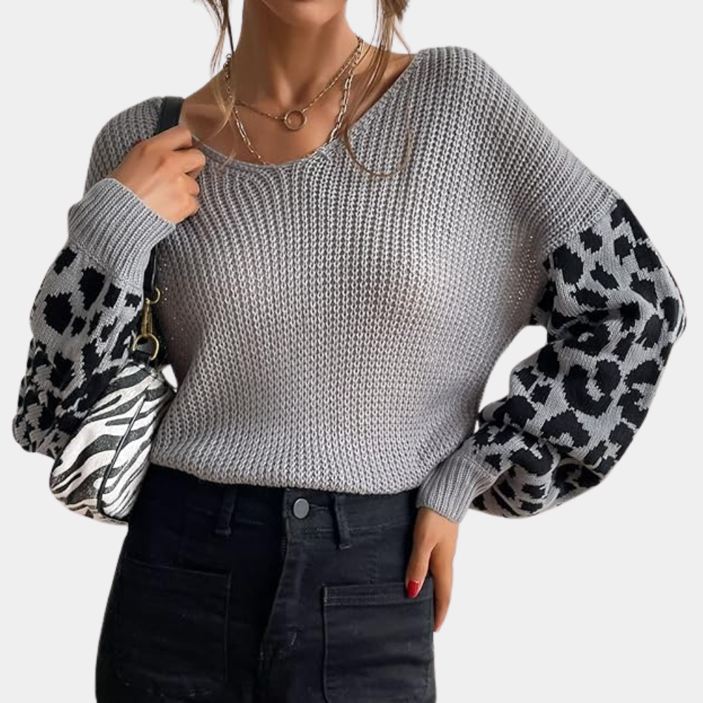 Grijze gebreide trui met luipaardprint mouwen, gedragen door vrouw met zwarte jeans en schoudertas. Modieuze dameskleding, herfststijl.