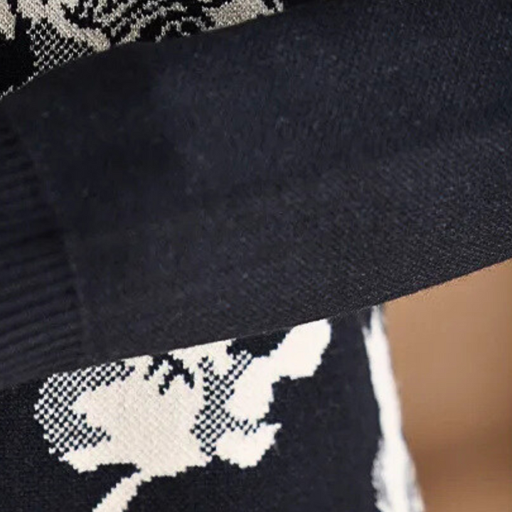Zwart-witte gebreide trui met abstract bloemenpatroon, close-up van mouw en textuur. Modieuze winterkleding, warme gebreide stof.
