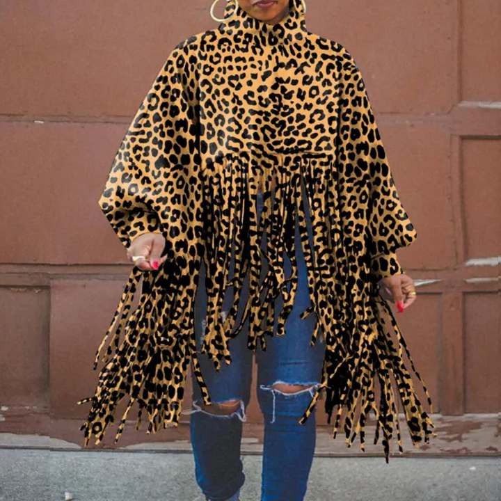 Vrouw draagt een modieuze luipaardprint poncho met franjes, gecombineerd met blauwe jeans. Trendy herfstkleding, opvallende dierenprint.