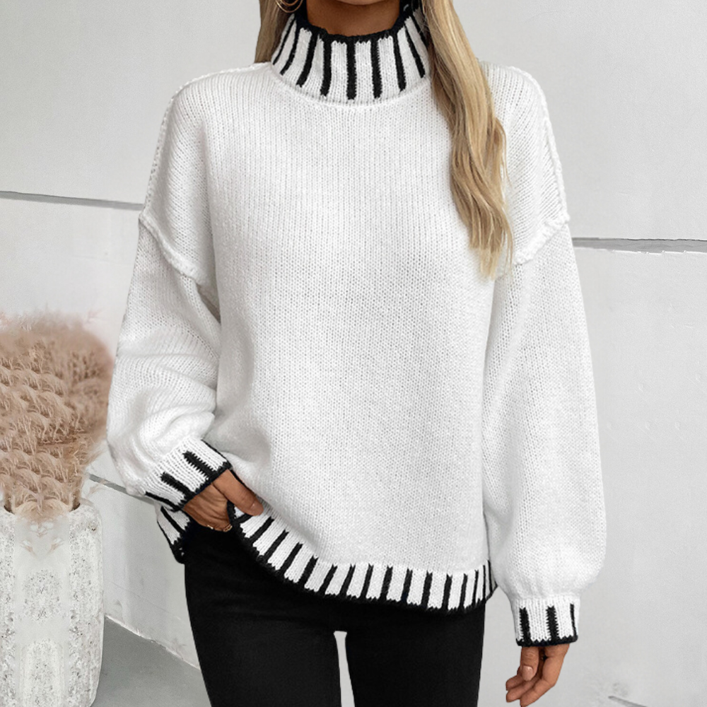 Vrouw draagt witte trui met zwarte strepen op kraag, manchetten en zoom. Modieuze dameskleding, herfst-winter stijl, casual outfit.