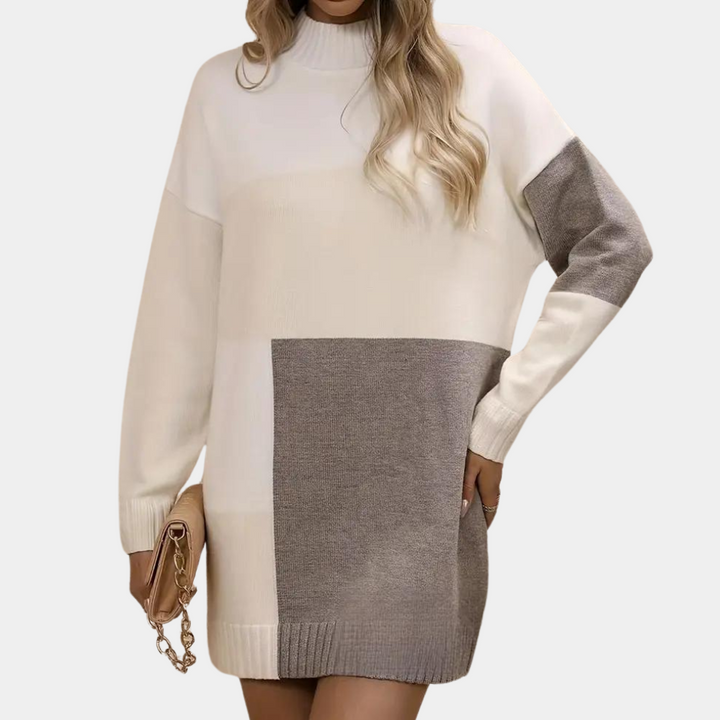 Vrouw in oversized gebreide trui met kleurvlakken, beige en grijs, lange mouwen, modieuze herfstkleding, handtas met ketting.