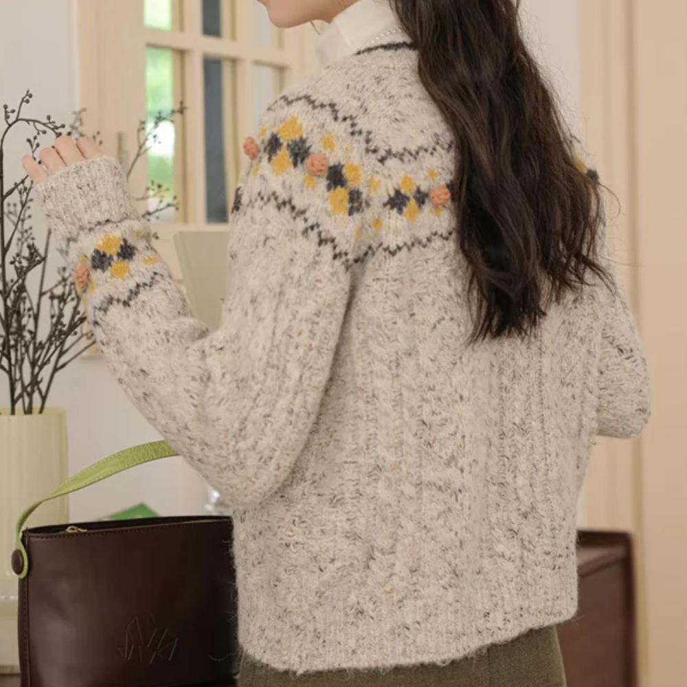 Grijze gebreide trui met kleurrijk Noors patroon, gedragen door vrouw. Perfect voor herfstmode. Stijlvolle, warme dameskleding.