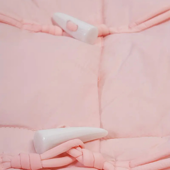 Roze gewatteerde jas met witte hoornknopen, close-up. Modieuze winterkleding, trendy damesjas, warme en stijlvolle buitenkleding.