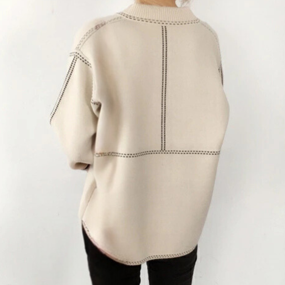 Beige oversized trui met zwarte stiksels, gedragen door persoon. Modieuze dameskleding, casual stijl, comfortabele pasvorm, herfst-winter mode.