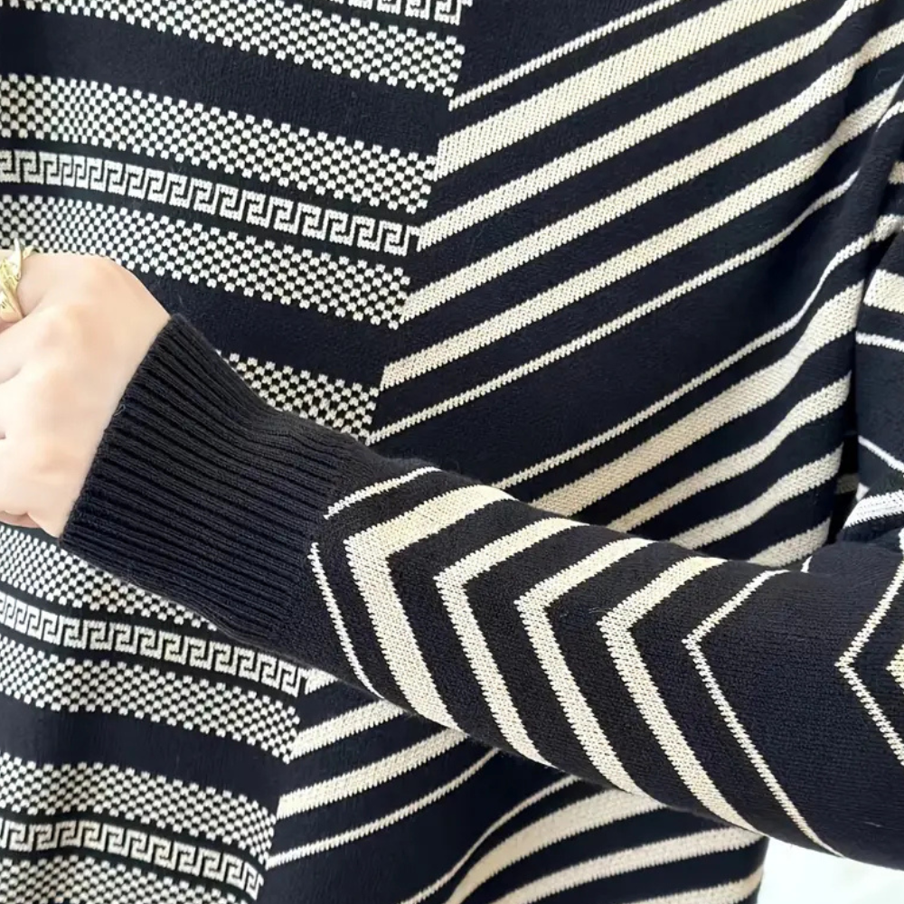Zwart-witte trui met geometrisch patroon, waaronder zigzag en Griekse sleutelmotieven. Moderne damesmode, stijlvolle winterkleding.