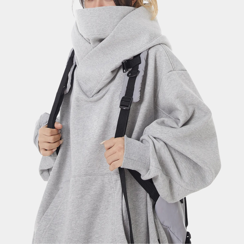 Grijze oversized hoodie met hoge kraag en zwarte rugzak. Comfortabele streetwear mode, ideaal voor casual en urban stijlen.