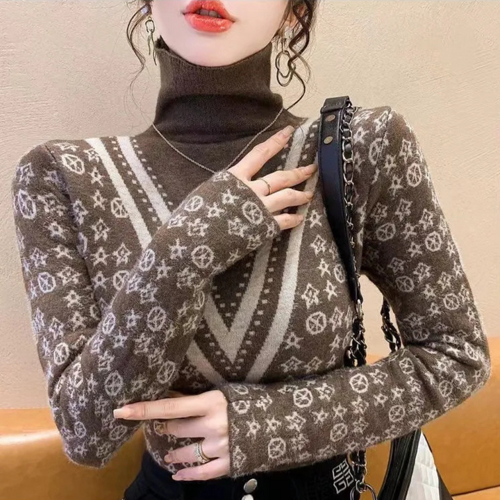Vrouw draagt bruine coltrui met geometrisch patroon, ketting en zwarte schoudertas. Modieuze herfstkleding, trendy damesmode, stijlvolle outfit.