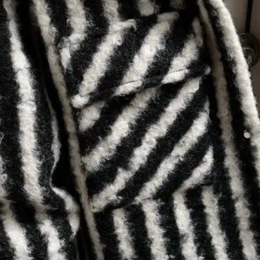 Zwart-wit gestreepte wollen stof met textuur, close-up. Geschikt voor modeontwerp, winterkleding, hoogwaardige textielmaterialen.