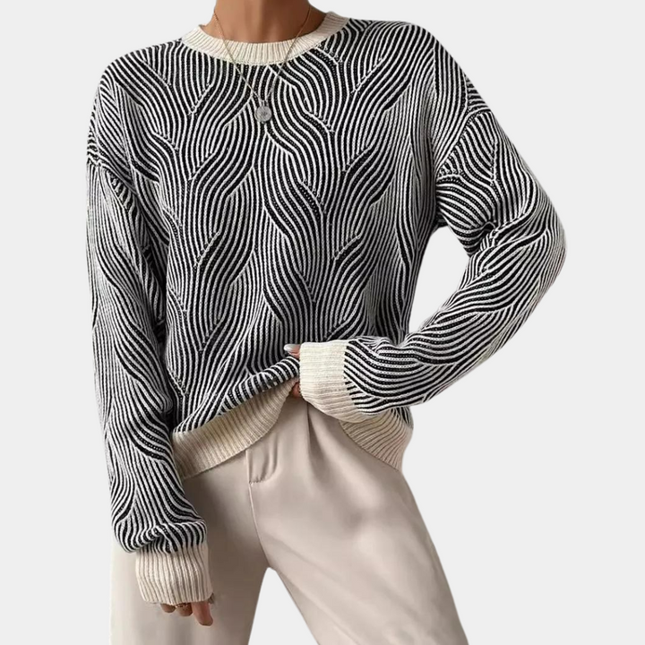 Zwart-witte trui met golvend patroon, lange mouwen en ronde hals, gedragen door model. Modieuze dameskleding, herfst-winter stijl.