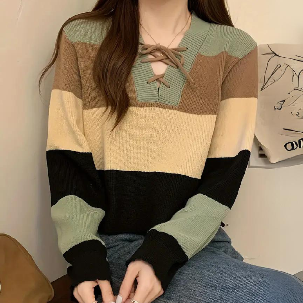 Vrouw draagt een gestreepte trui met vetersluiting in beige, bruin, groen en zwart. Modieuze dameskleding, herfsttrui, casual outfit.