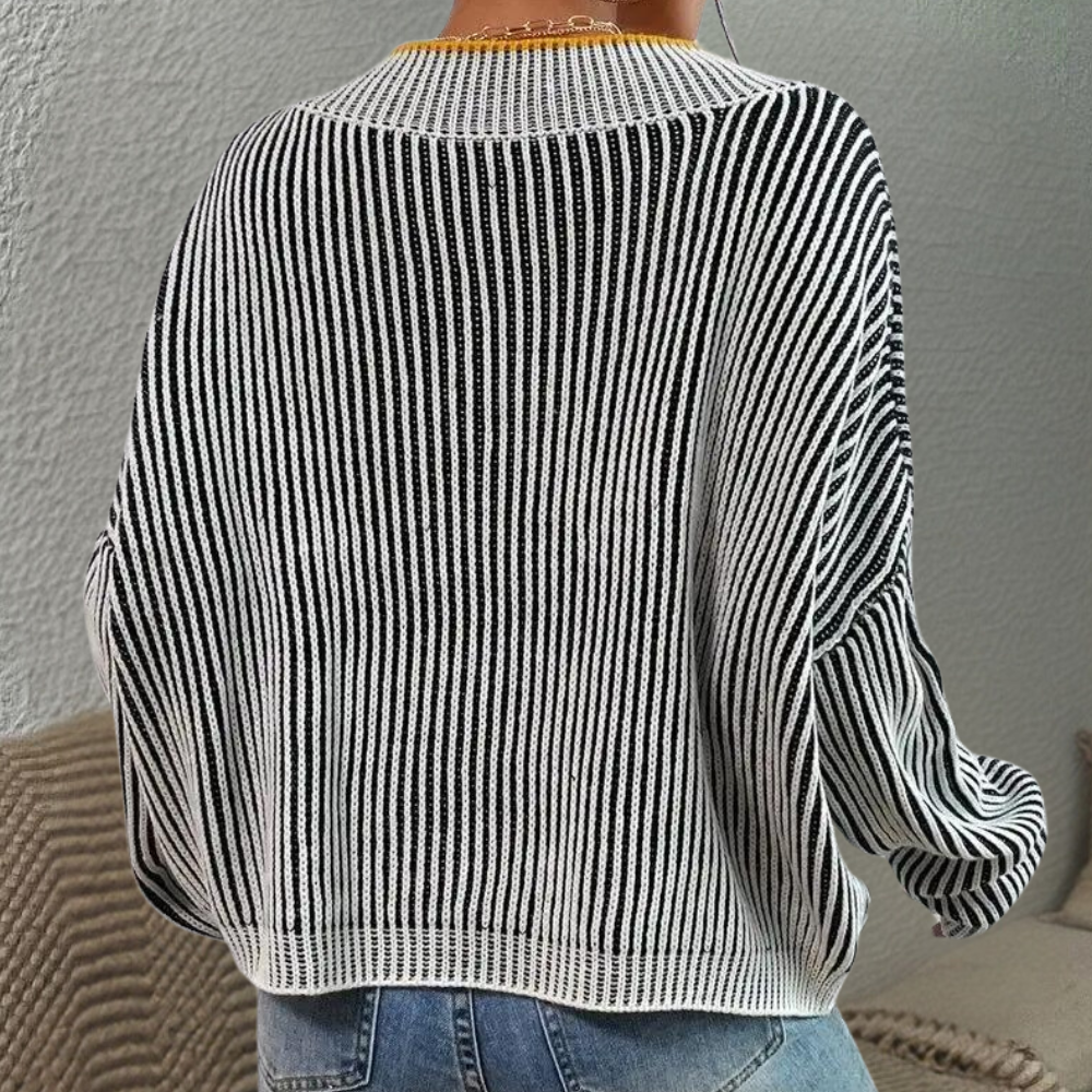 Gestreepte zwart-witte trui, oversized pasvorm, gedragen door persoon met spijkerbroek. Modieuze dameskleding, casual stijl, comfortabele outfit.