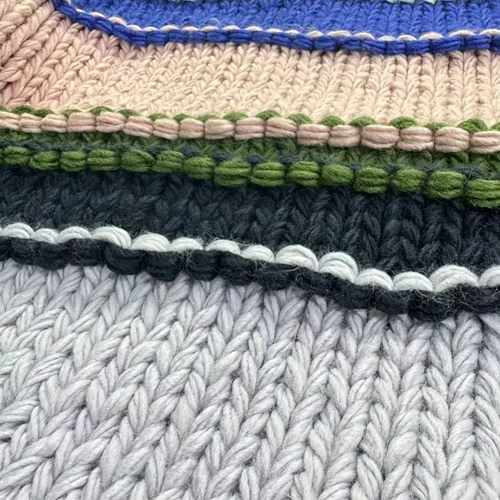 Gestapelde gebreide dekens in pastelkleuren, close-up. Zachte textuur, handgemaakt breiwerk, kleurrijke randen. Perfect voor interieurdecoratie.