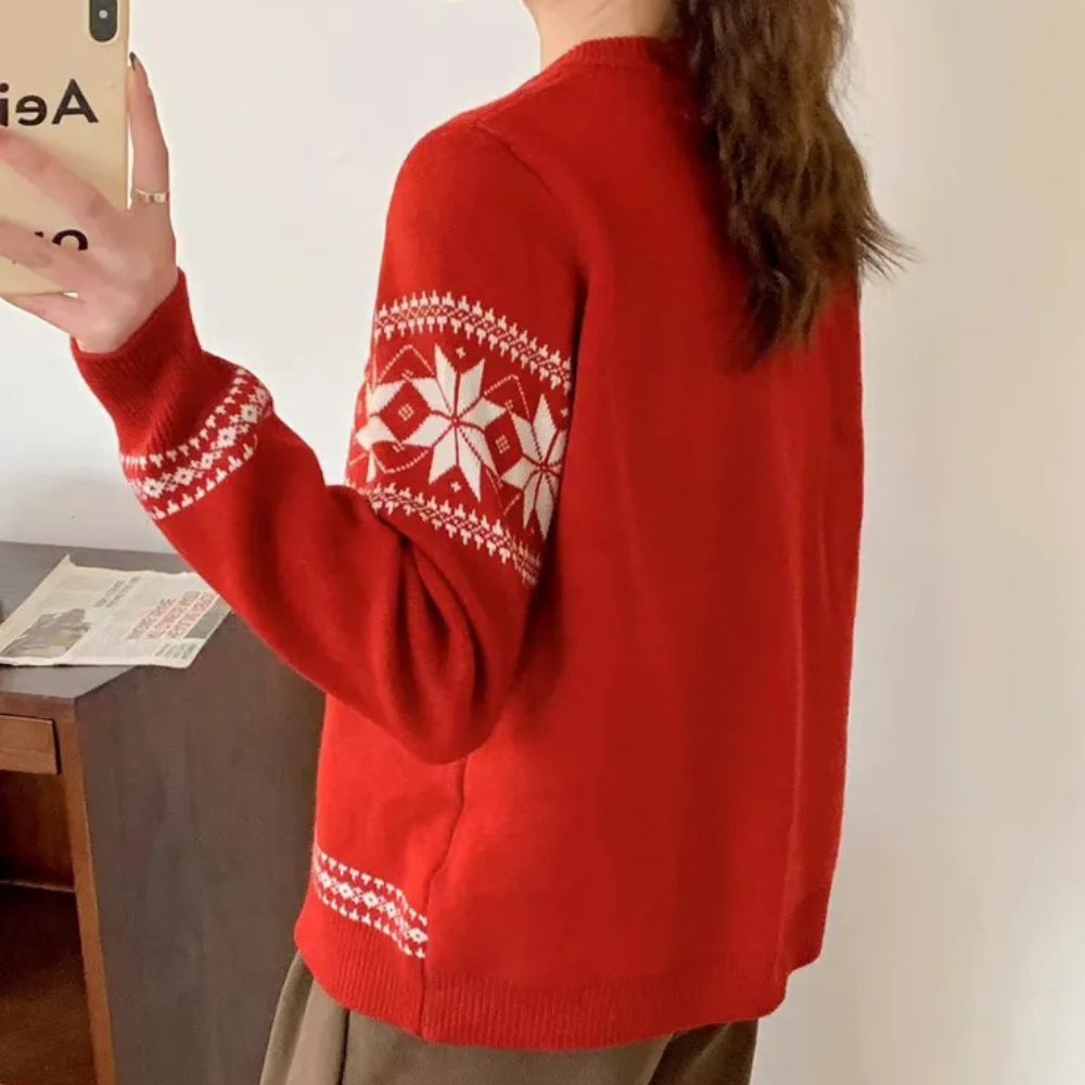 Rode kersttrui met witte sneeuwvlokprint, gedragen door persoon die selfie maakt. Perfect voor wintermode en feestdagen.