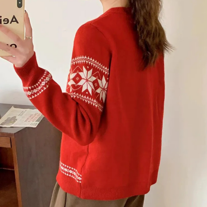 Rode kersttrui met witte sneeuwvlokprint, gedragen door persoon die selfie maakt. Perfect voor wintermode en feestdagen.