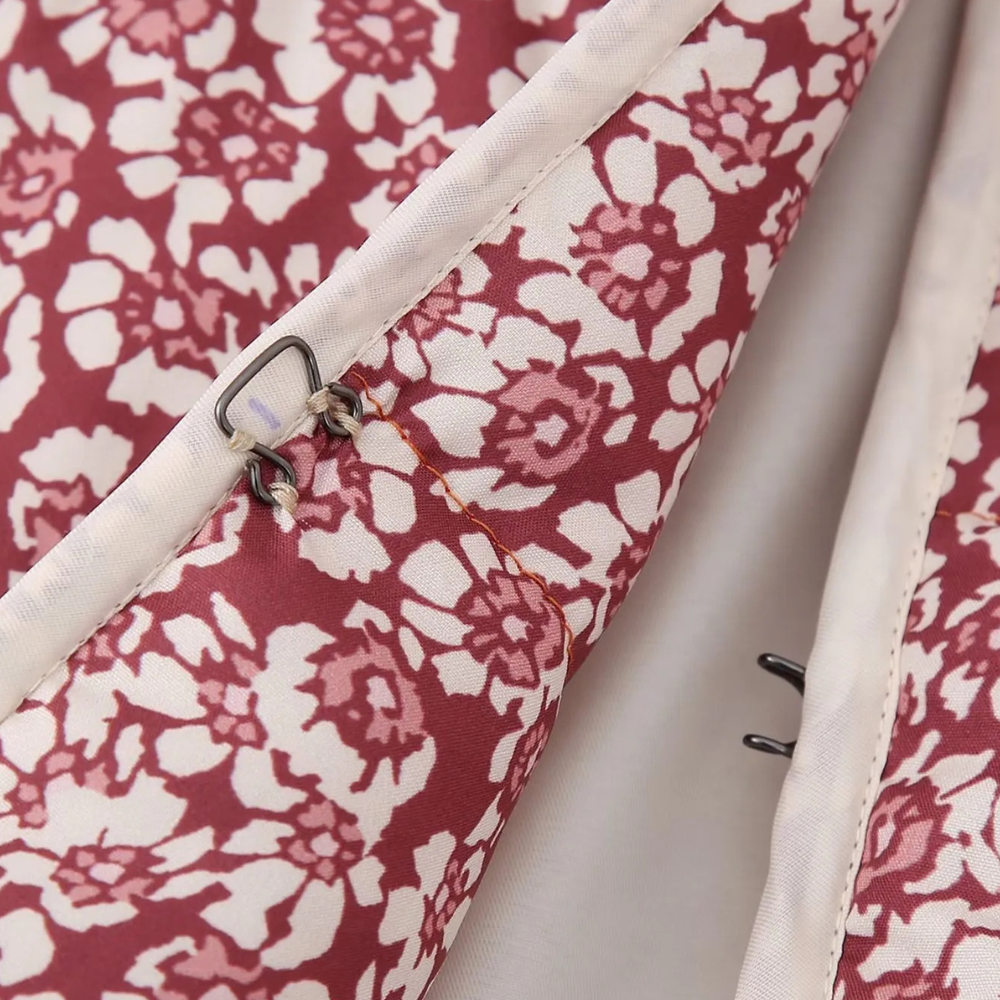 Rode bloemenprint stof met metalen haaksluiting, close-up. Ideaal voor kledingontwerp, naaiprojecten, textielaccessoires.