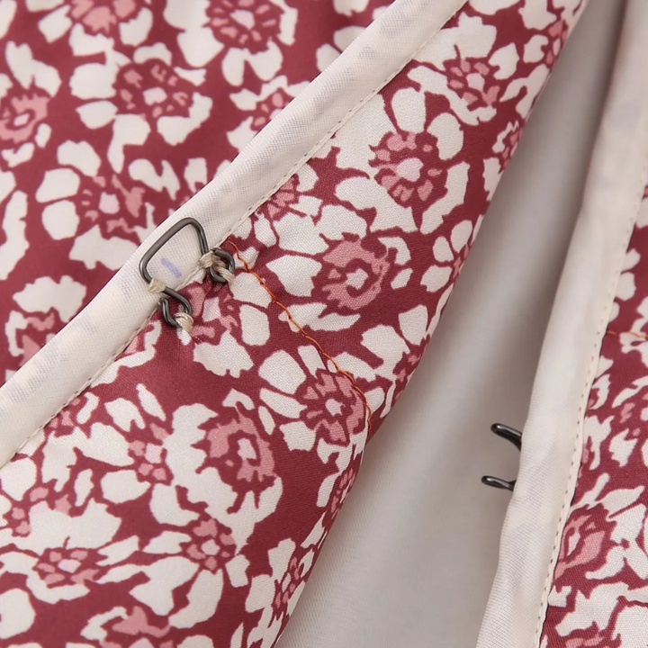 Rode bloemenprint stof met metalen haaksluiting, close-up. Ideaal voor kledingontwerp, naaiprojecten, textielaccessoires.