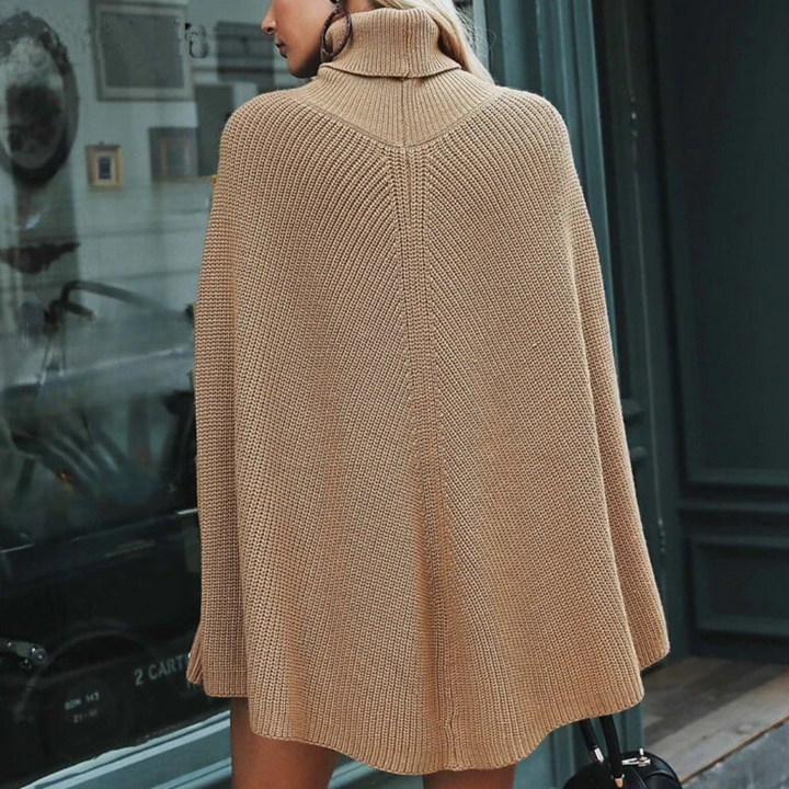 Beige gebreide poncho met col, gedragen door vrouw op straat. Modieuze herfstkleding, warme damescape, stijlvolle casual outfit.