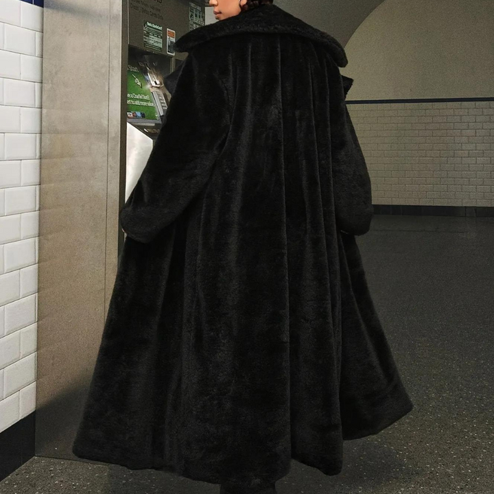 Zwarte lange bontjas, gedragen door persoon in metrostation. Stijlvolle wintermode, luxe uitstraling, warme kleding, stedelijke achtergrond.