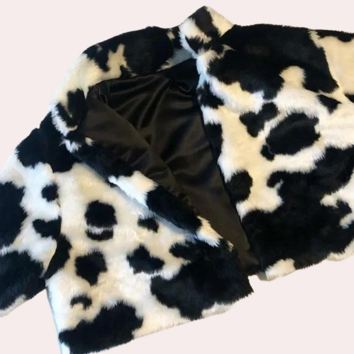 Zwart-witte koeienprint bontjas, openliggend met zichtbare zwarte voering, modieuze winterkleding, synthetisch bont, trendy damesjas.