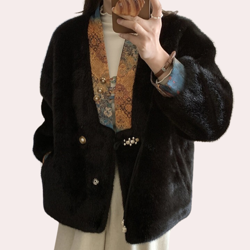 Zwarte faux fur jas met kleurrijke, geborduurde kraag en decoratieve knopen, gedragen door persoon. Modieuze winterkleding, trendy damesjas.