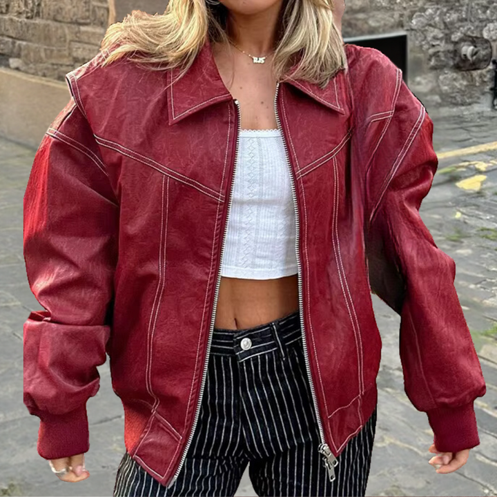 Rode leren jas dames, oversized pasvorm, modieuze streetwear, witte top, gestreepte broek, stedelijke achtergrond, casual herfstkleding.