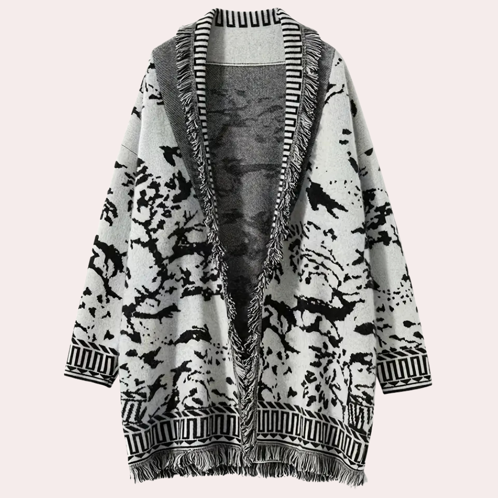 Grijze oversized cardigan met zwart-wit abstract patroon, franjes en gestreepte boorden. Perfect voor herfstmode en casual outfits.
