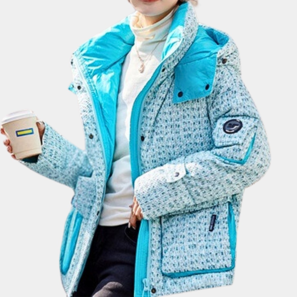 Vrouw in stijlvolle blauwe winterjas met patroon, houdt een koffiebeker vast. Modieuze dameskleding, warme jas voor koude seizoenen.