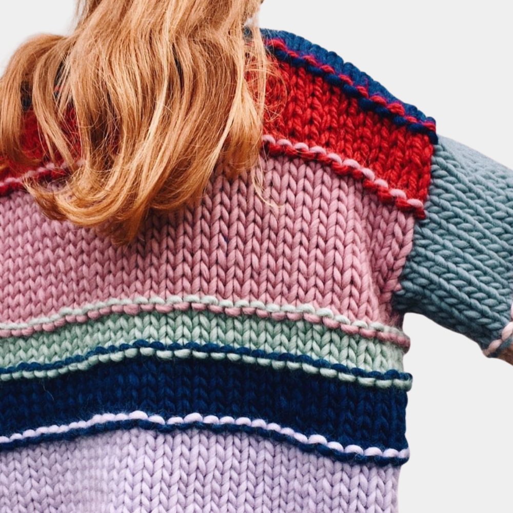 Vrouw met kleurrijke gebreide trui, strepen in rood, roze, groen en blauw. Modieuze winterkleding, handgemaakt breiwerk, trendy damesmode.
